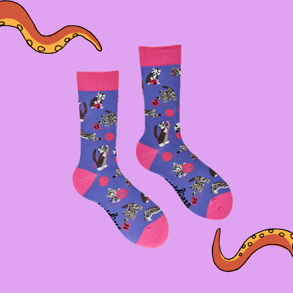 
                      
                        A pair of socks depicting cats playing with wool. Purple legs, pink cuff, heel and toe.
                      
                    