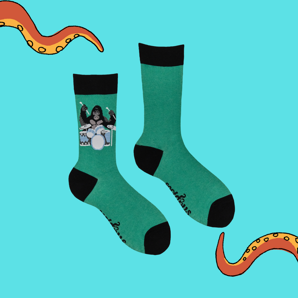 
                      
                        A pair of socks featuring a drumming gorilla. Green legs, black heel, toe and cuff. 
                      
                    