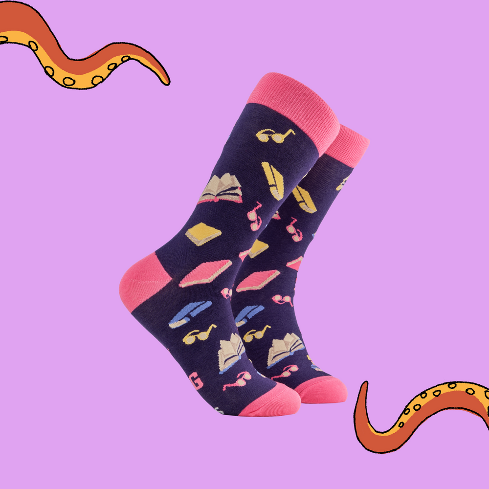 A pair of socks depicting books and reading glasses. Purple legs, pink cuff, heel and toe.