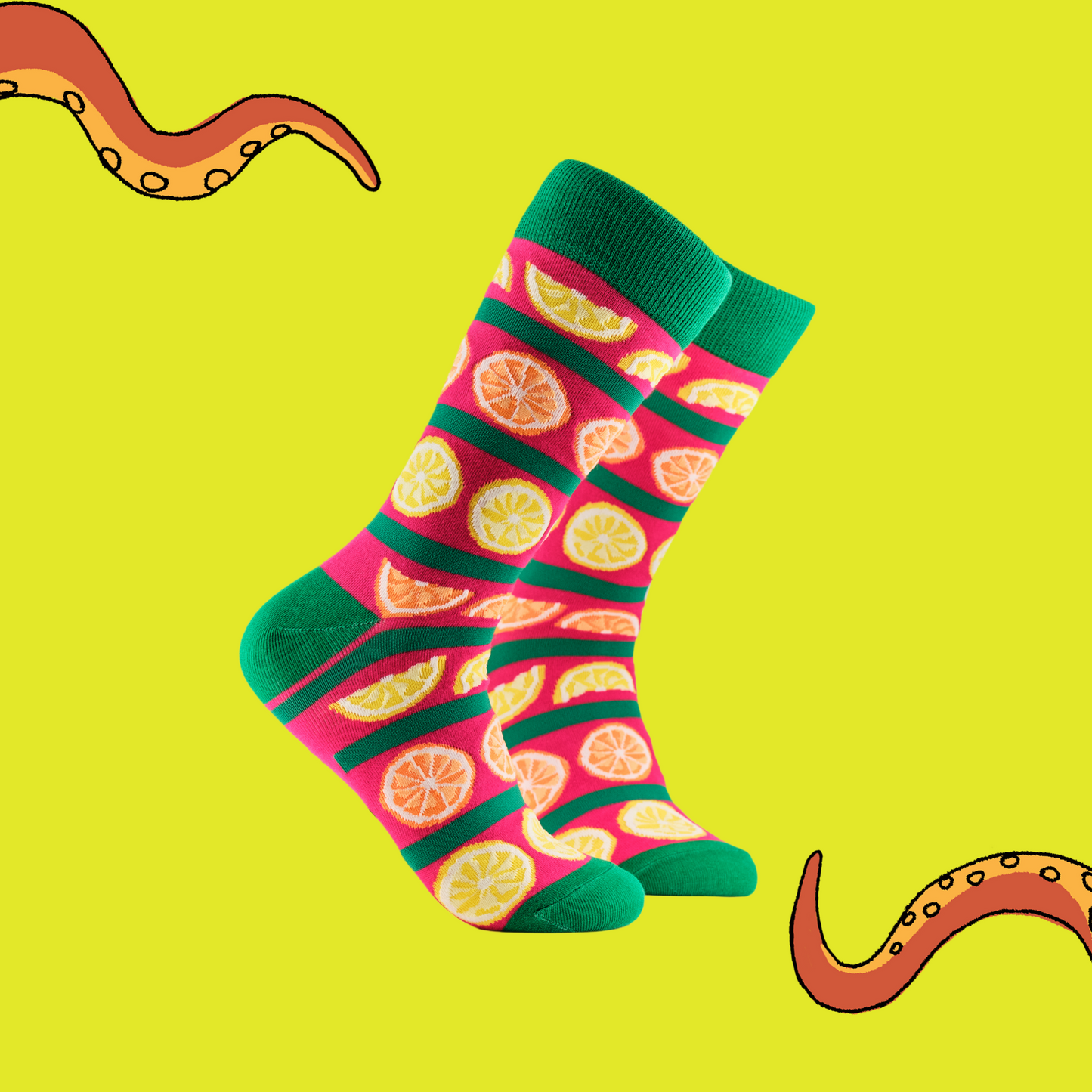 A pair of socks depicting oranges and lemons. Pink and green legs, green cuff, heel and toe.