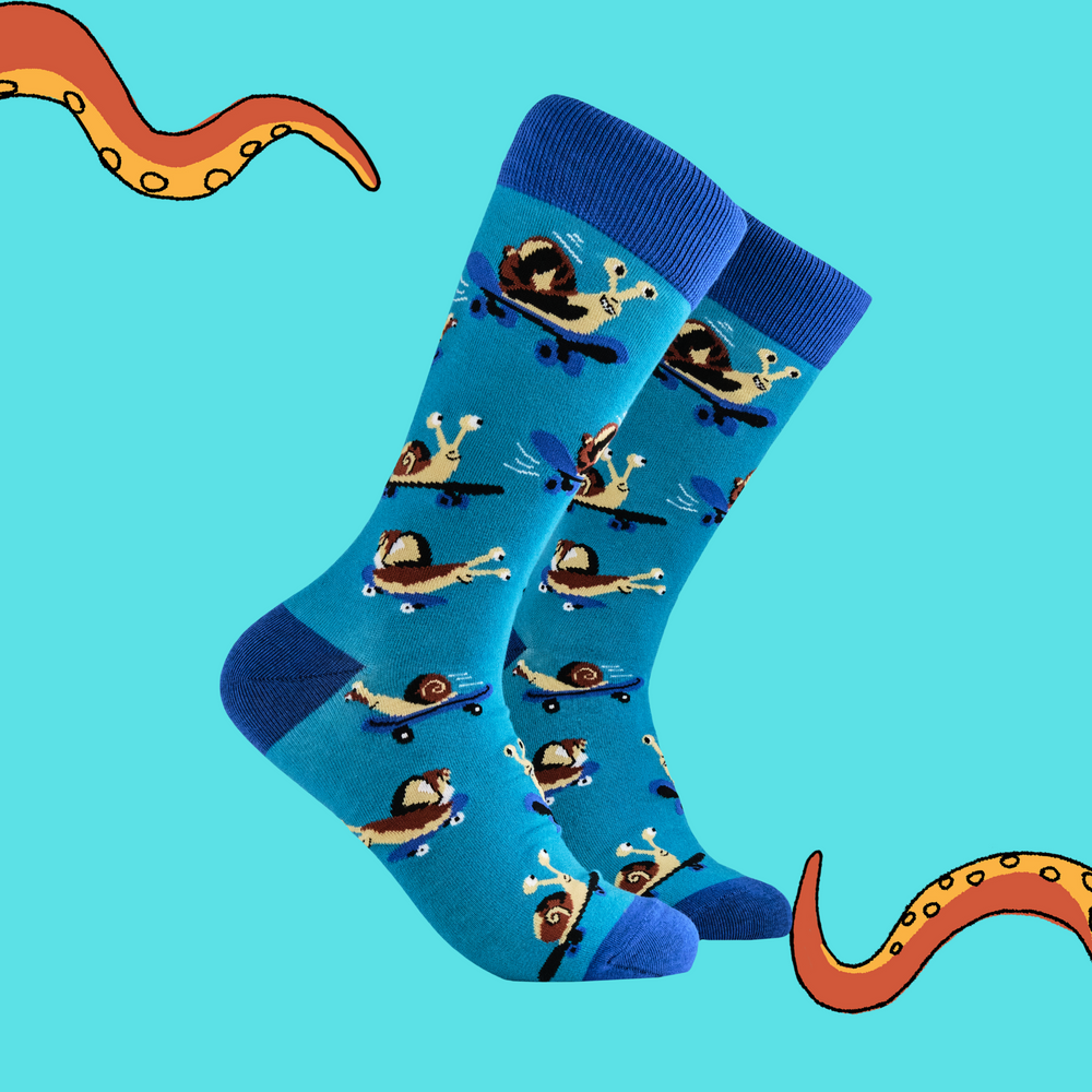 A pair of socks depicting a snail on a skateboard. Blue legs, light blue heel, toe and cuff. 