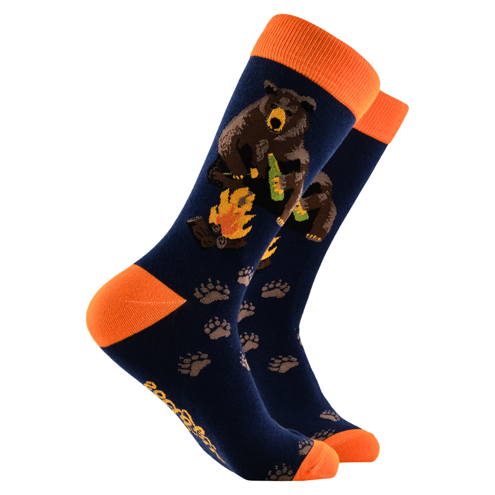 Bear Socks - Camp Out. A pair of socks depicting a bear sitting by a campfire. Dark blue legs, orange cuff, heel and toe. 