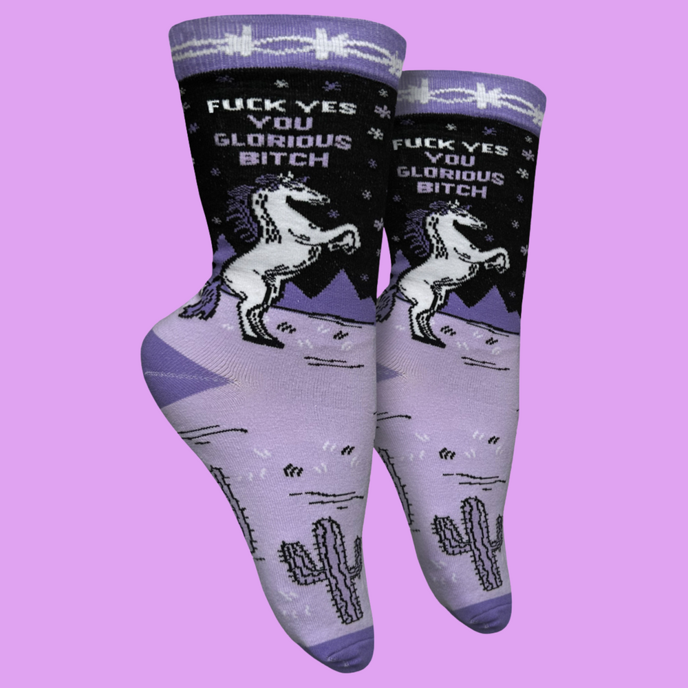 
                  
                    A pair of socks with a unicorn motif and a bold sweary slogan. Purple legs with deep purple toes, heel and cuff.
                  
                