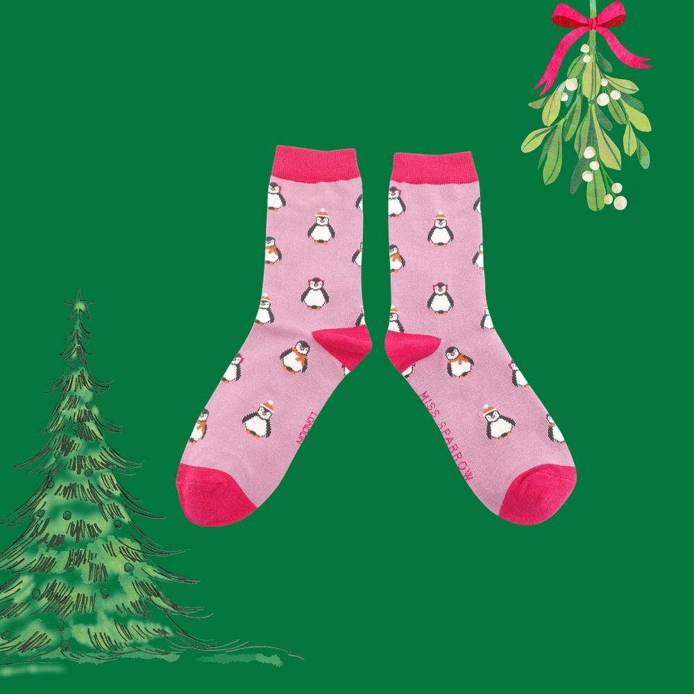 
                      
                        A pair of socks depicting penguins wearing hats and scarves for the winter. Pink legs, bright pink toes, heels and cuffs. 
                      
                    