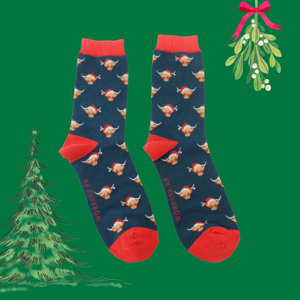 A pair of socks with a festive highland cow pattern. Dark blue legs, red heel, toe and cuff. 