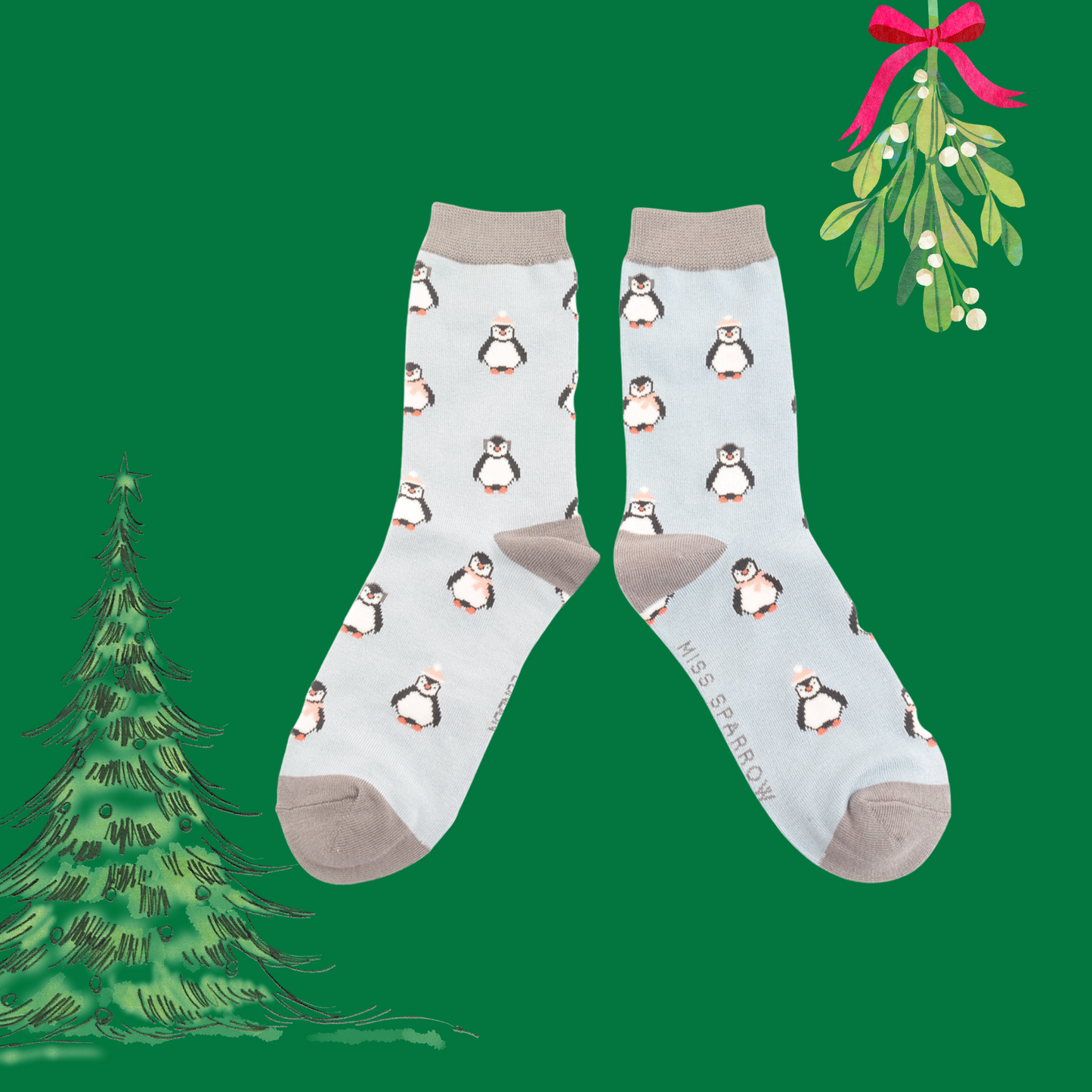 A pair of socks depicting penguins wearing hats and scarves for the winter. Light blue legs, grey toes, heels and cuffs. 