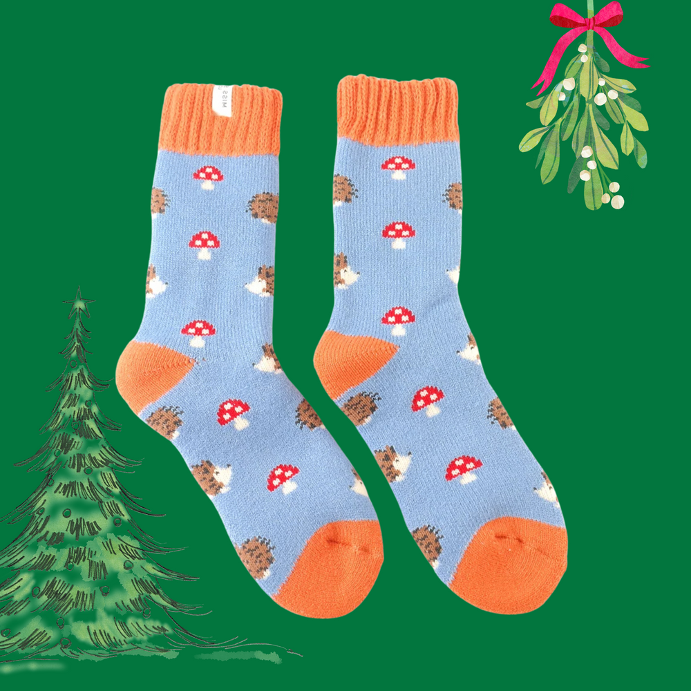 A pair of socks with a hedgehog and toadstool motif. Blue legs. Orange cuff, toe and heel. 