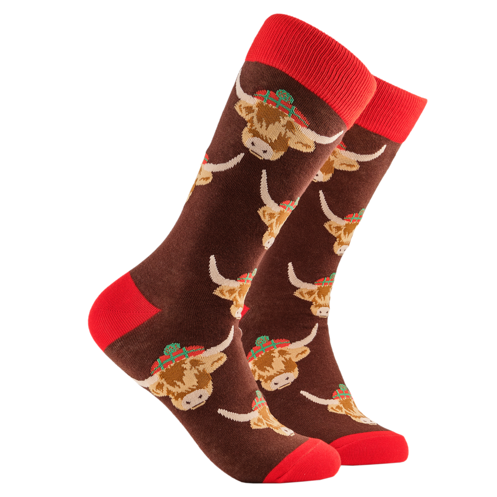 Highland Cow Socks. A pair of socks depicting highland cows wearing tartan hats. Brown legs, red cuff, heel and toe.