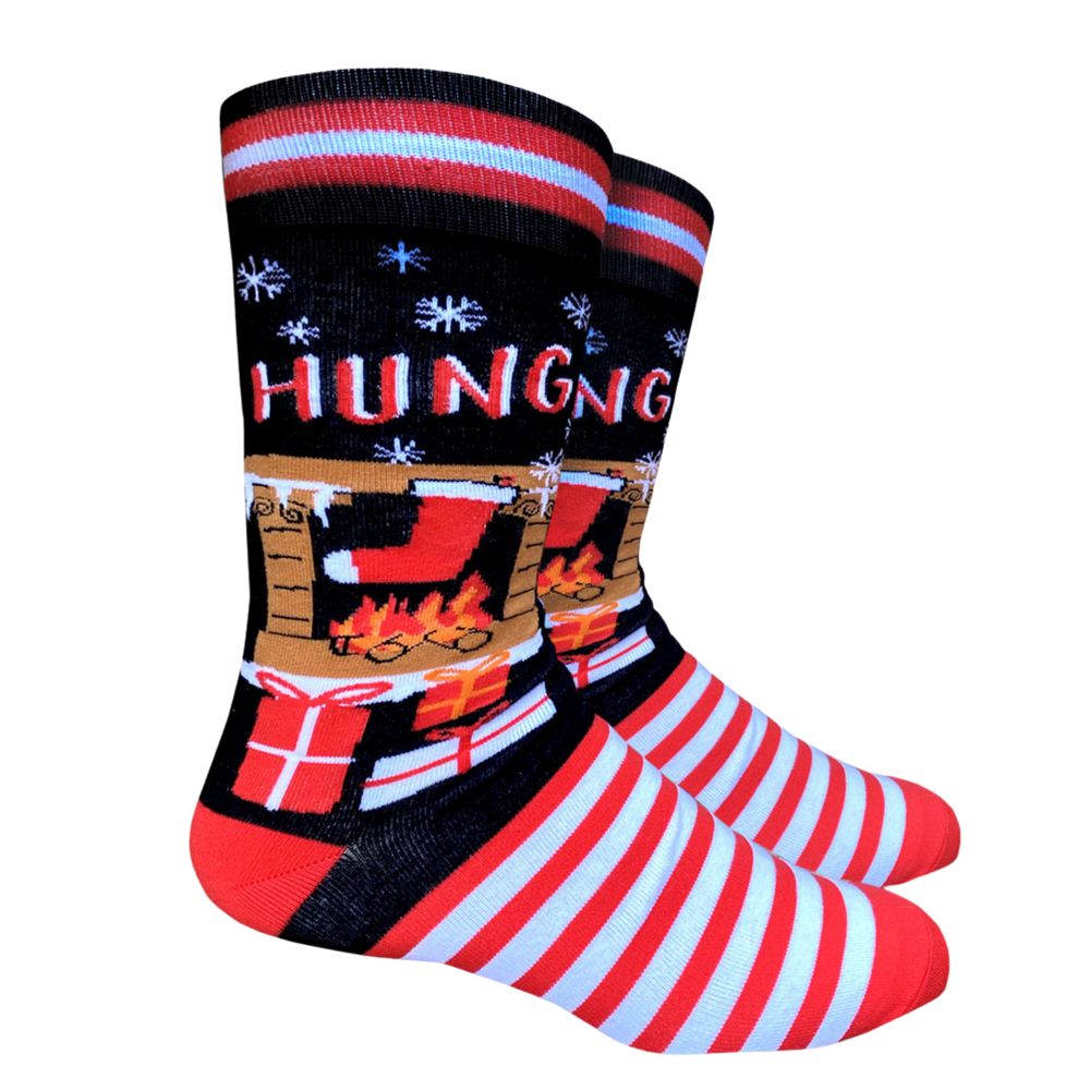 Hung Slogan Socks. A pair of Christmas themed socks with a stocking hanging over a  fireplace. Striped toes and cuff. Red heel. 