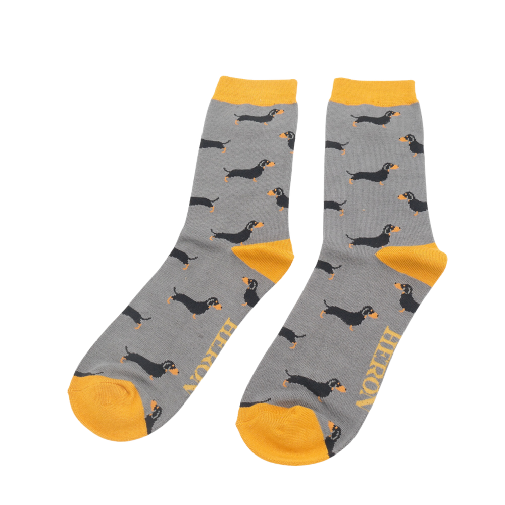 
                  
                    A pair of socks featuring a sausage dog pattern. Grey legs, yellow cuffs, heel and toe.
                  
                