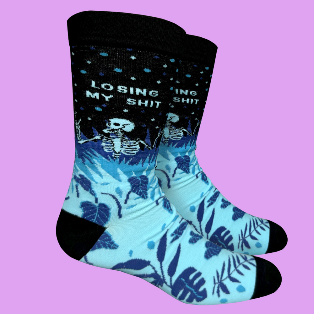 
                  
                    A blue and black pair of socks with a skeleton and the slogan Losing My S**t on the ankle. Black heel, toe and cuff.
                  
                