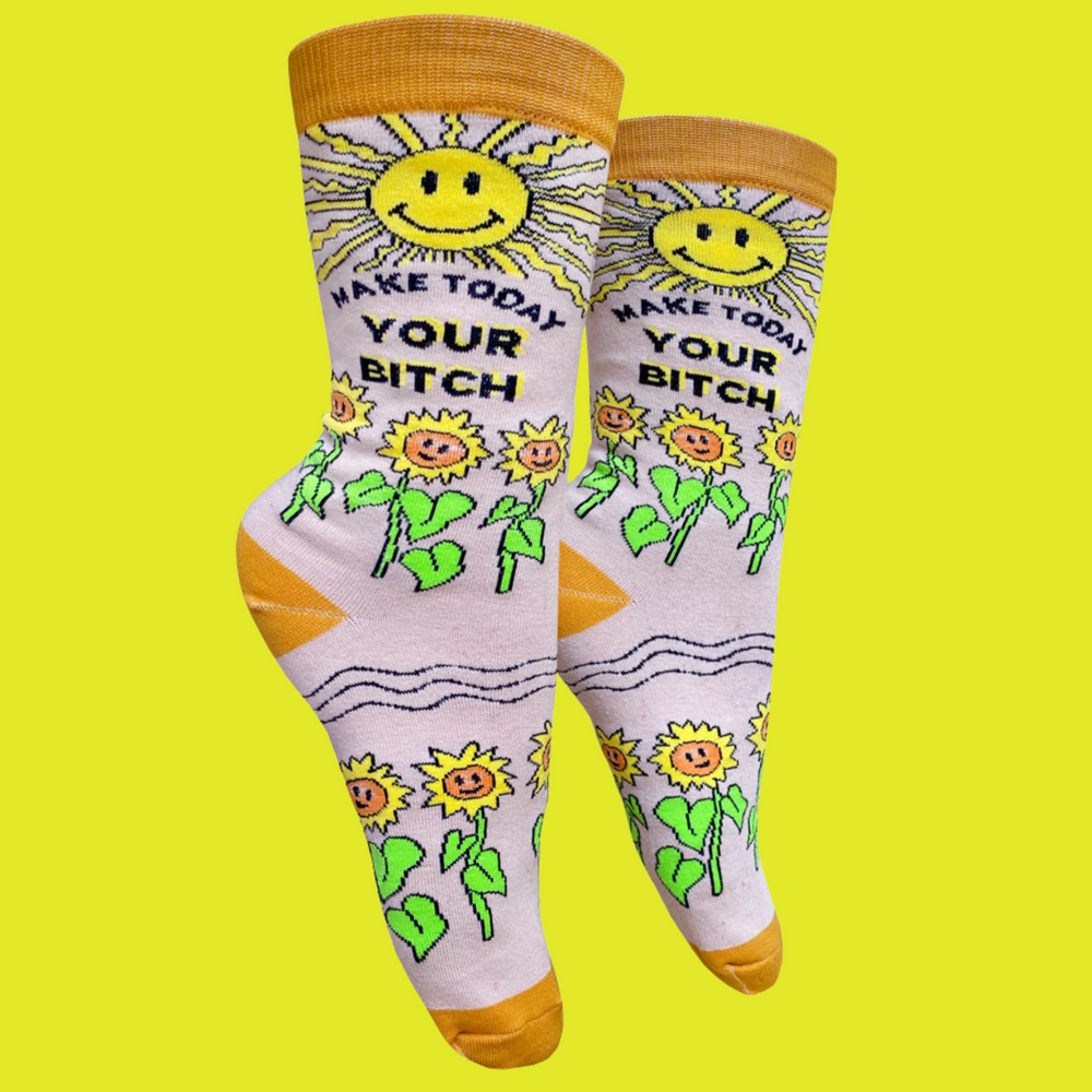 Make Today Your B**tch Socks. A pair of socks depicting the sun and sunflowers with a bold sweary slogan. Orange toes, cuff and heel.