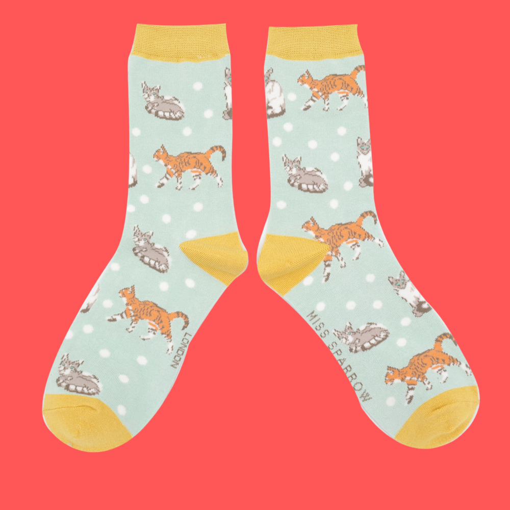 
                      
                        A pair of socks with a cat motif and spots pattern. Light blue legs, yellow heel, toe and cuff. 
                      
                    