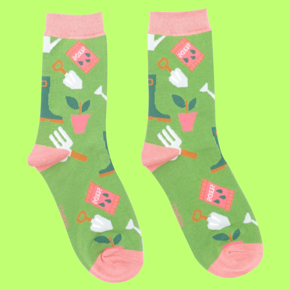 
                      
                        A pair of socks featuring gardening tools. Green legs, pink heel, toe and cuff. 
                      
                    