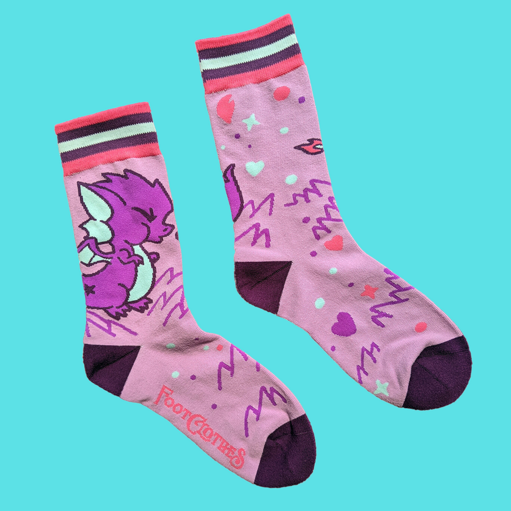 
                      
                        A pair of socks featuring a cute dragon motif. Pink legs, purple heel, toe and cuff. 
                      
                    