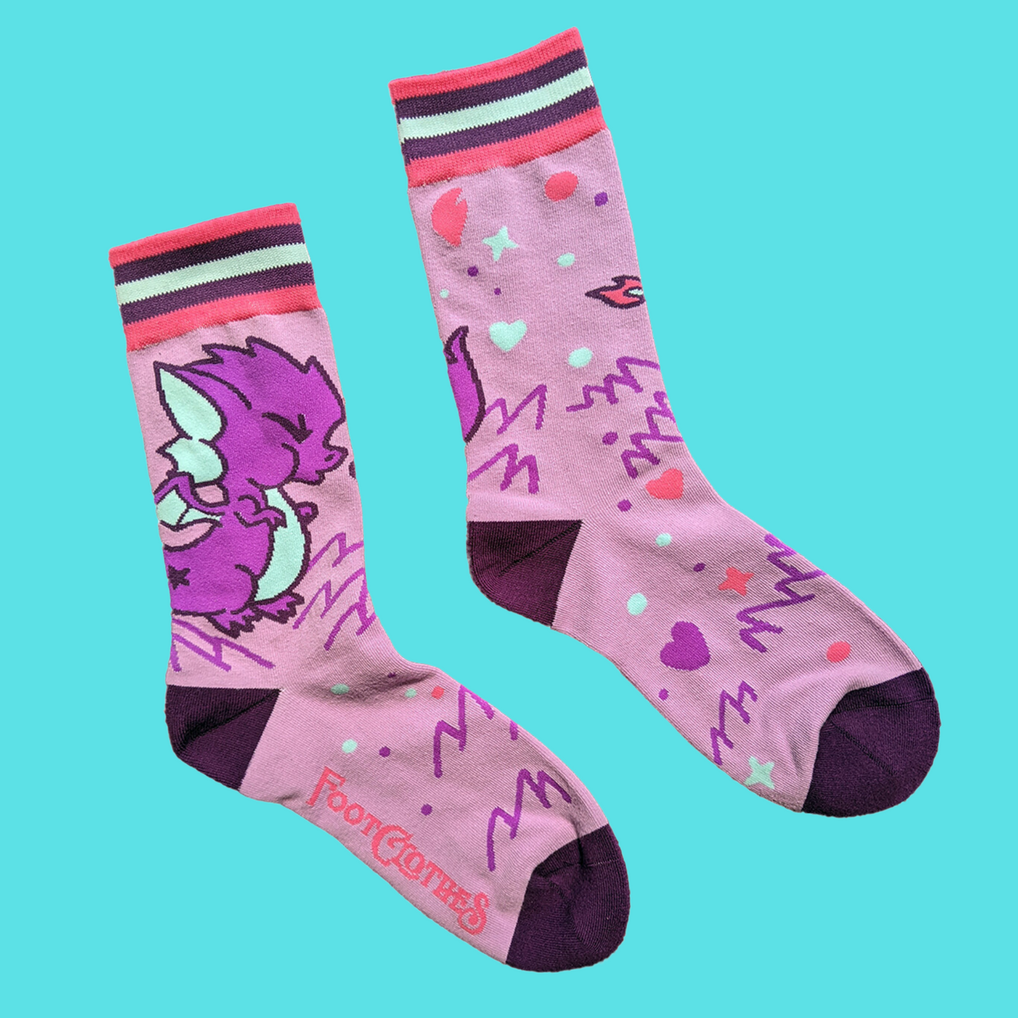 A pair of socks featuring a cute dragon motif. Pink legs, purple heel, toe and cuff. 