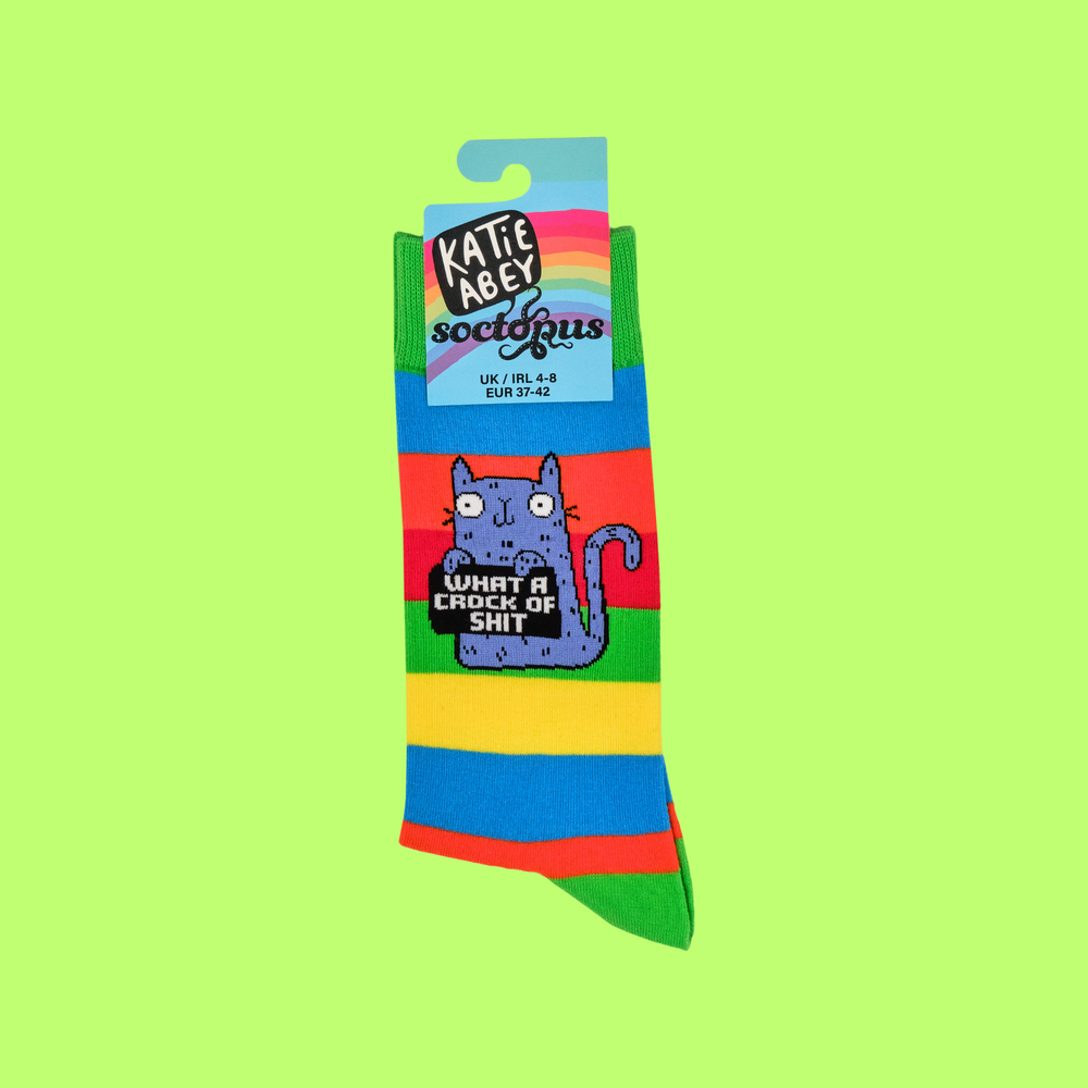 
                      
                        A pair of socks featuring a cute cat holding a sweary sign. Multicolored striped legs. 
                      
                    