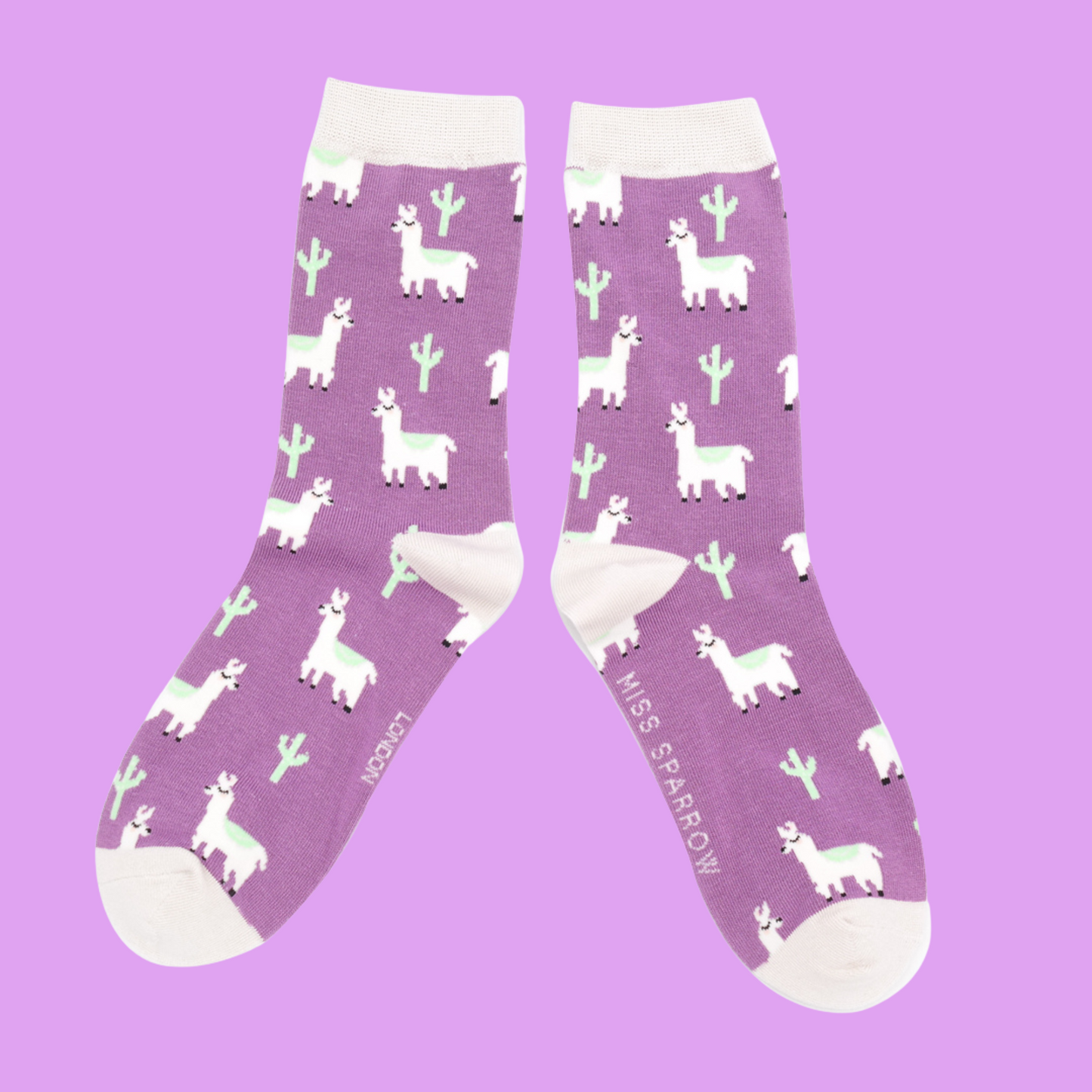 
                  
                    Llama & Cactus Bamboo Socks - Miss Sparrow. A pair of socks depicting cacti and Llamas. Pink legs, white cuff, heel and toe. 
                  
                