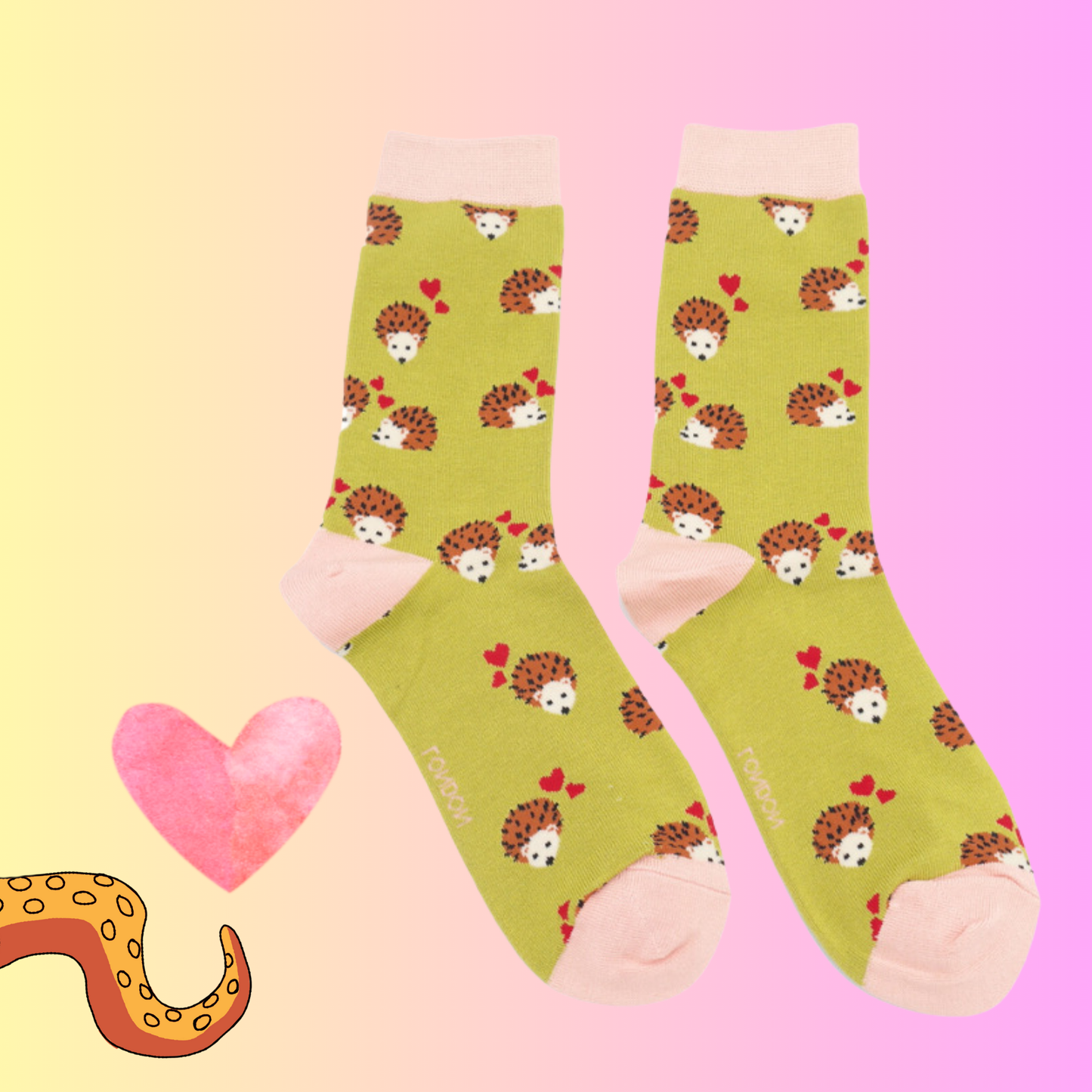 A pair of socks with a hedgehog and hearts motif. Yellow legs, pink heel, toe and cuff. 