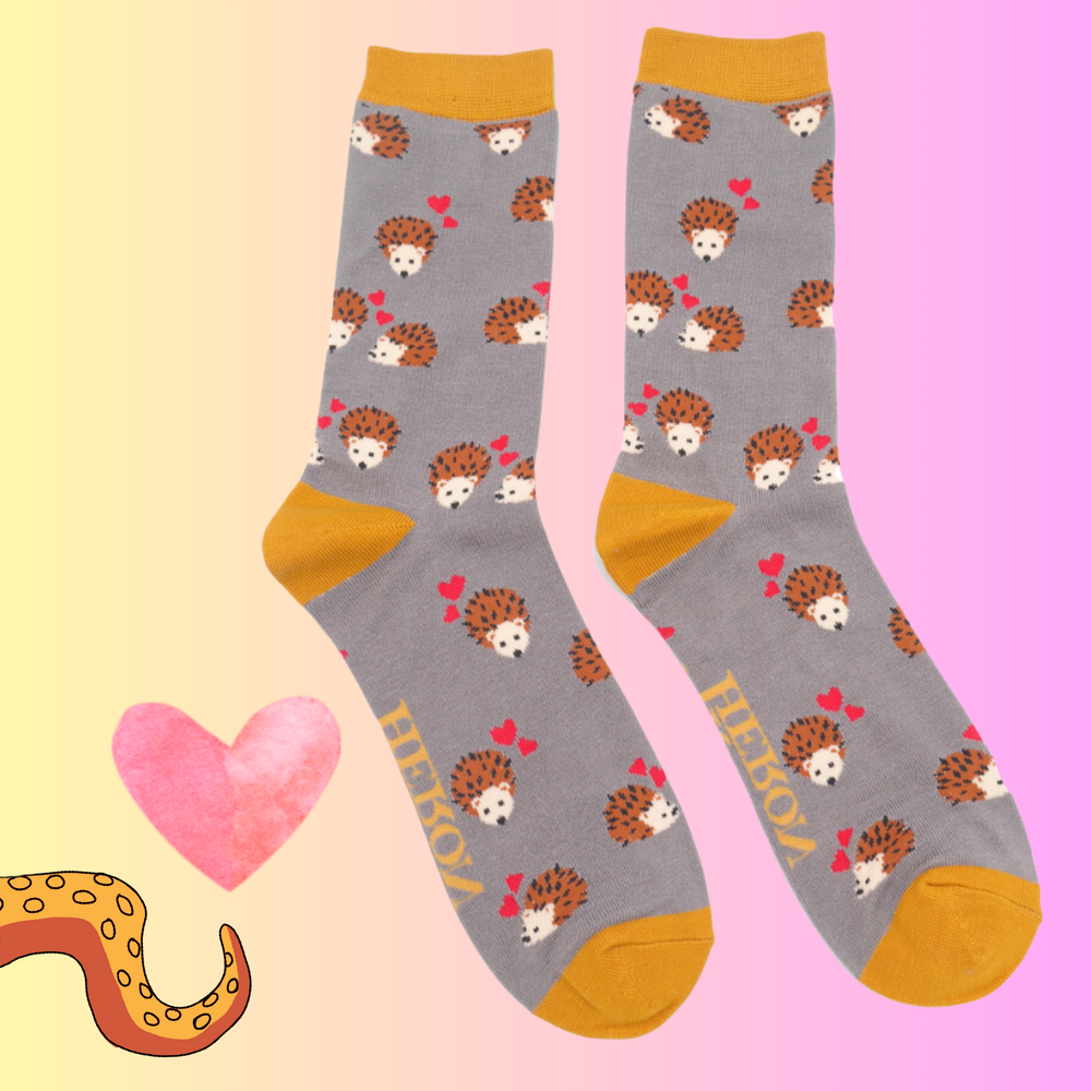 
                      
                        A pair of socks with a hedgehog and hearts motif. Grey legs, yellow heel, toe and cuff. 
                      
                    