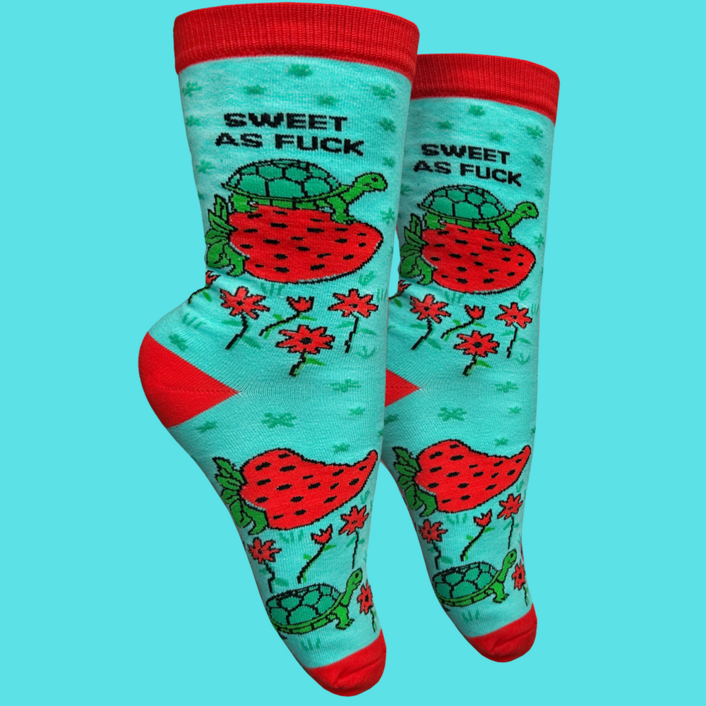 
                      
                        A pair of socks depicting a tortoise riding a strawberry, with a bold sweary slogan. Red toes, cuff and heel.
                      
                    