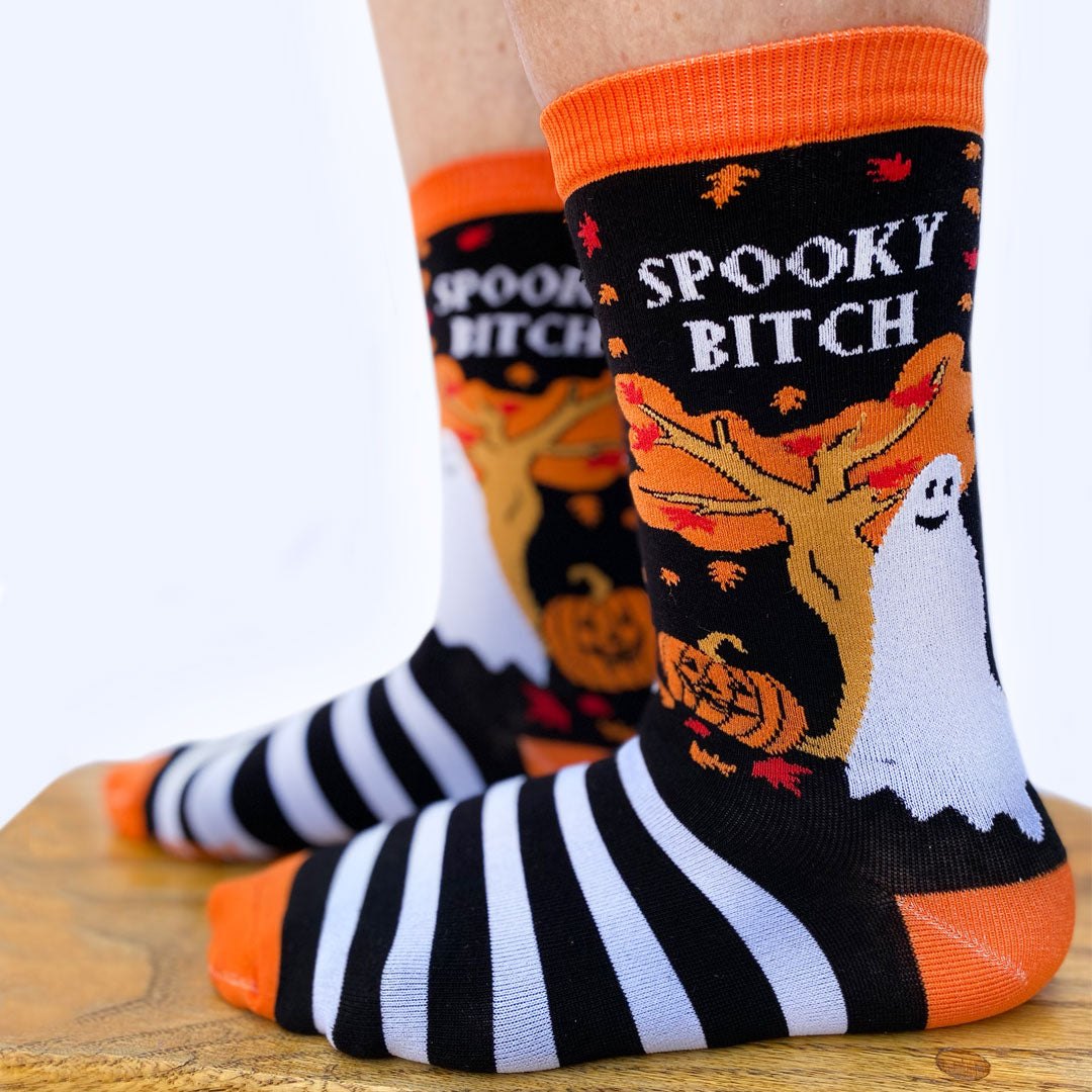 
                  
                    Model wearing a pair of socks depicting a selection of halloween items. Black and white legs, orange toe, cuff and heel. 
                  
                