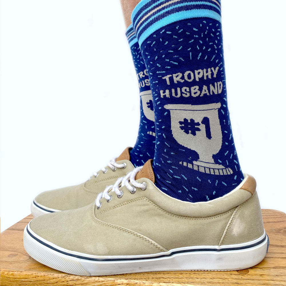 
                      
                        Model wearing a pair of socks with a Trophy Husband motif. Blue legs, light blue toe, heel and cuff. 
                      
                    