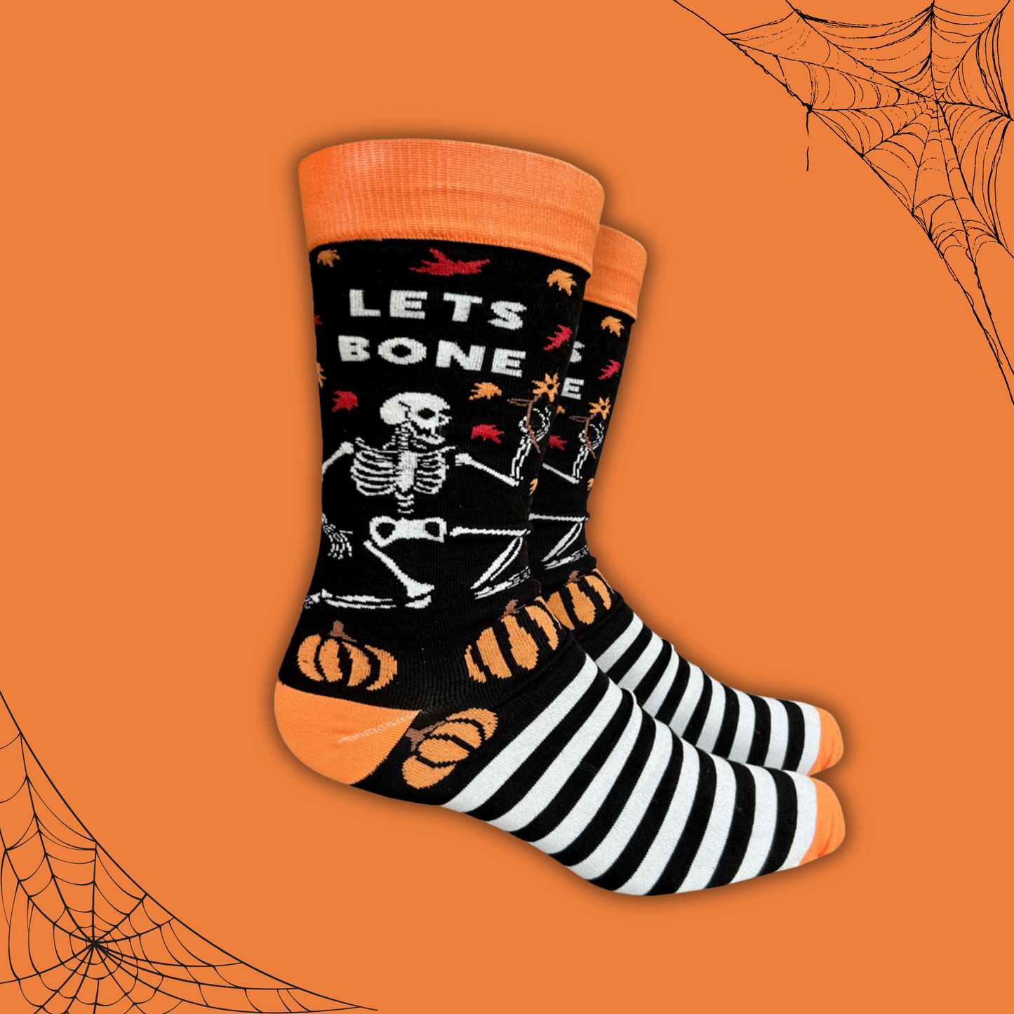 
                  
                    A pair of socks depicting a dancing skeleton and a bold slogan. Black and white stripes and halloween motifs. Orange toe, cuff and heel. 
                  
                