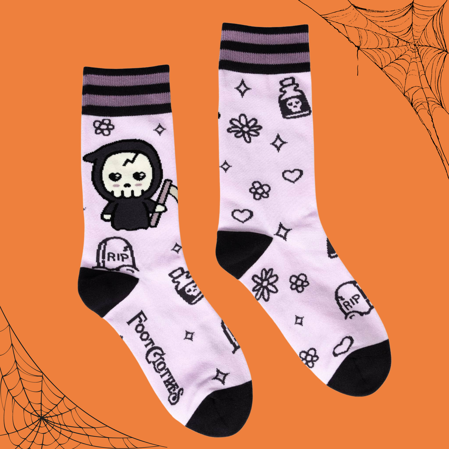 A pair of socks depicting a cartoon version of the grim reaper. Pastel pink socks, cute pattern. Black toes, cuff and heel. 