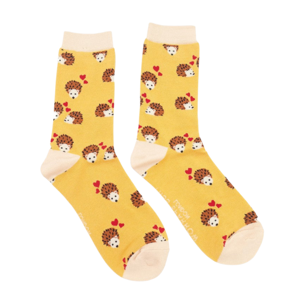 A pair of socks with a hedgehog and hearts motif. Yellow legs, pink heel, toe and cuff. 