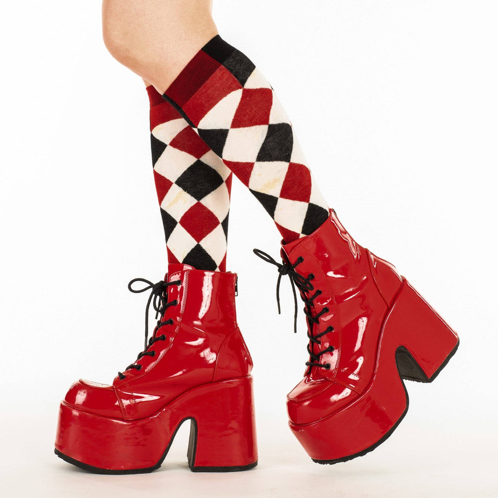 
                      
                        A model wearing a pair of knee high socks with a harlequin pattern. Black, white and red.
                      
                    