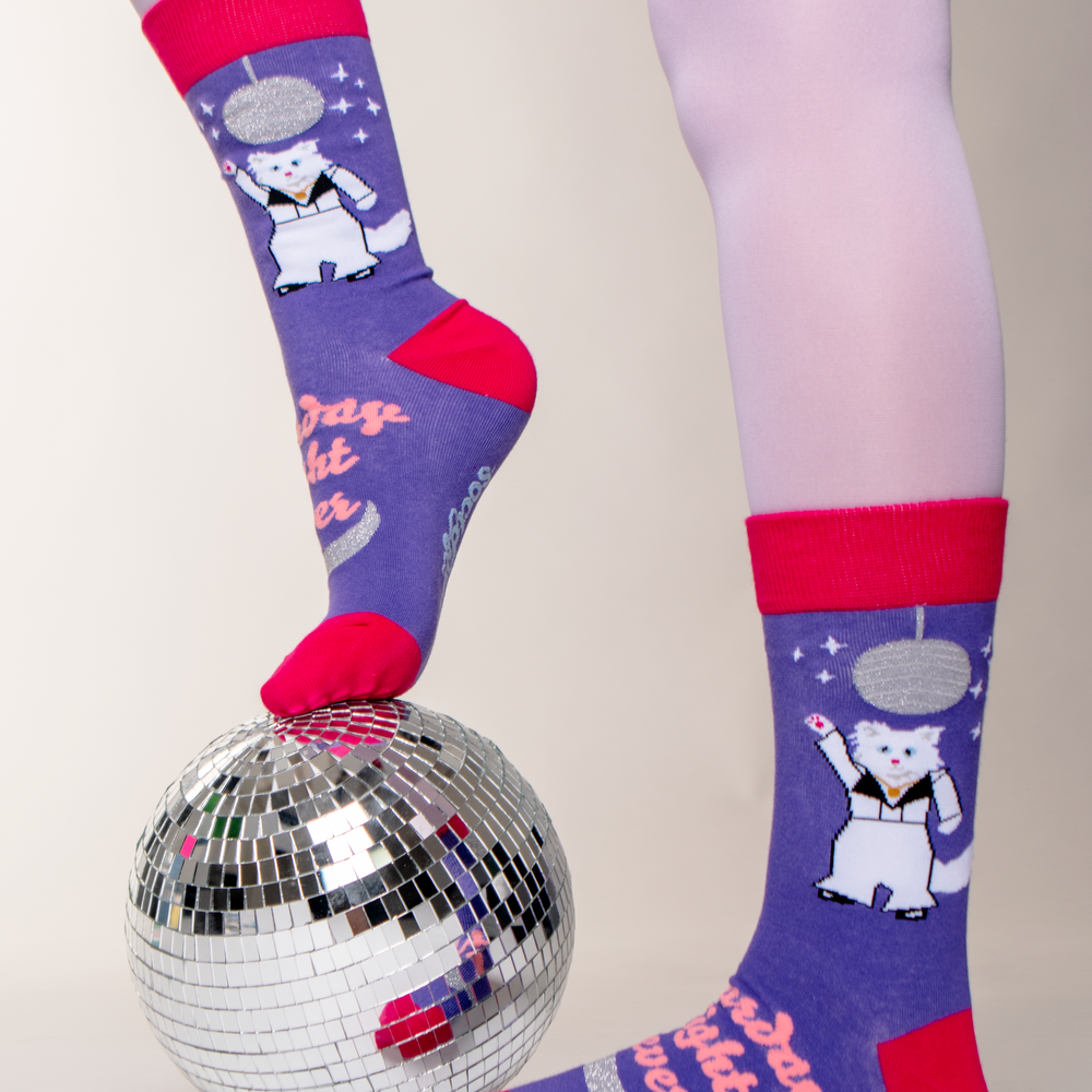 A model wearing a pair of disco cat Soctopus socks and a mirror ball. 