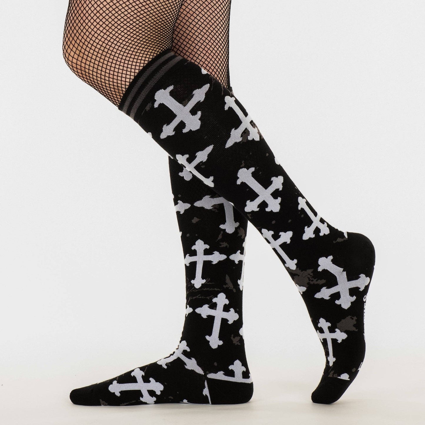 
                  
                    A model wearing a pair of knee high socks with a gothic cross pattern. Black and white. 
                  
                