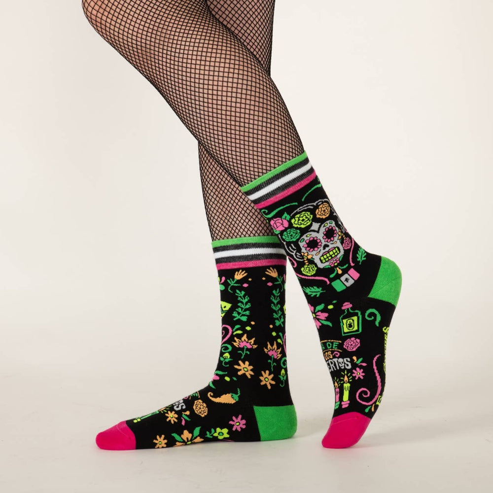 
                      
                        A model wearing a pair of socks with a day of the dead motif. Black legs, pink and green heel, toe and cuff. 
                      
                    