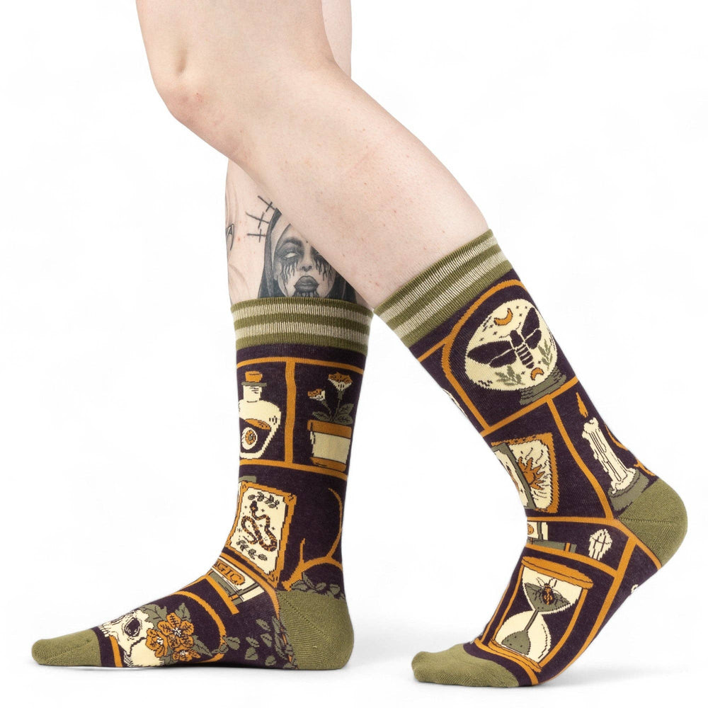 
                      
                        A model wearing a pair of socks depicting a collection of odd objects. Brown legs, green, heel, toe and cuff. 
                      
                    