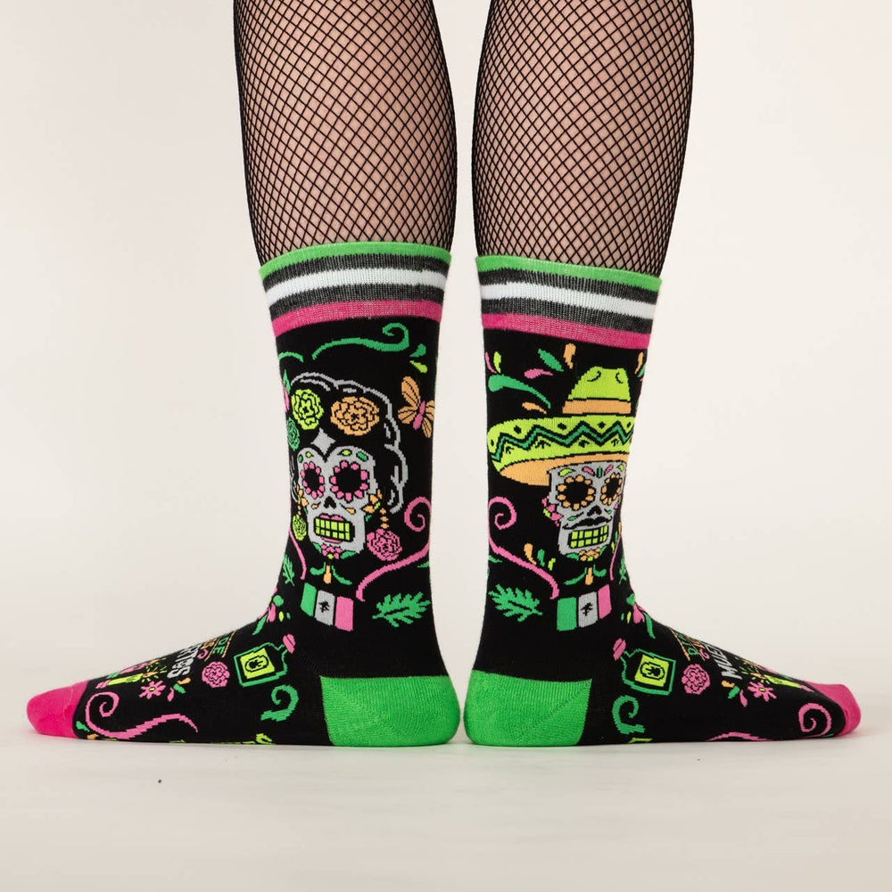 
                      
                        A model wearing a pair of socks with a day of the dead motif. Black legs, pink and green heel, toe and cuff. 
                      
                    