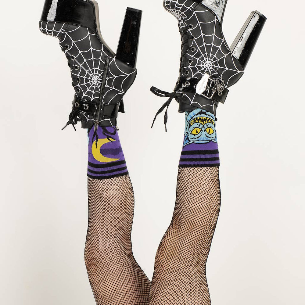 
                      
                        A model wearing a pair of socks featuring the cheshire cat. Purple legs, black heel, cuff and toe. 
                      
                    