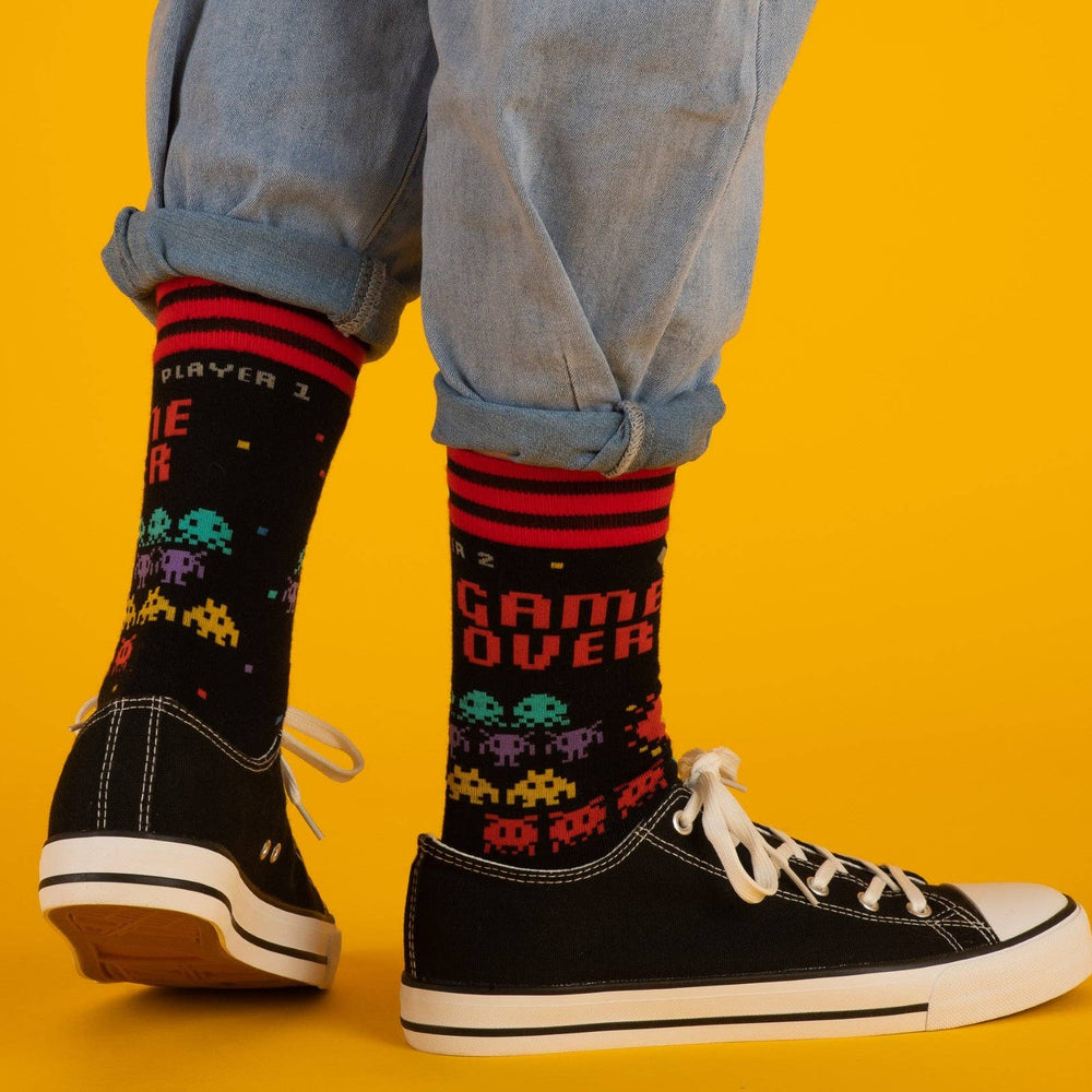 
                      
                        A model wearing a pair of socks featuring space invaders and game over. Black legs, red heel, toe and cuff. 
                      
                    