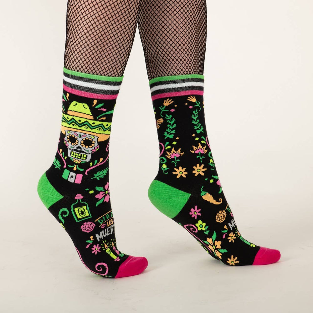 
                      
                        A model wearing a pair of socks with a day of the dead motif. Black legs, pink and green heel, toe and cuff. 
                      
                    