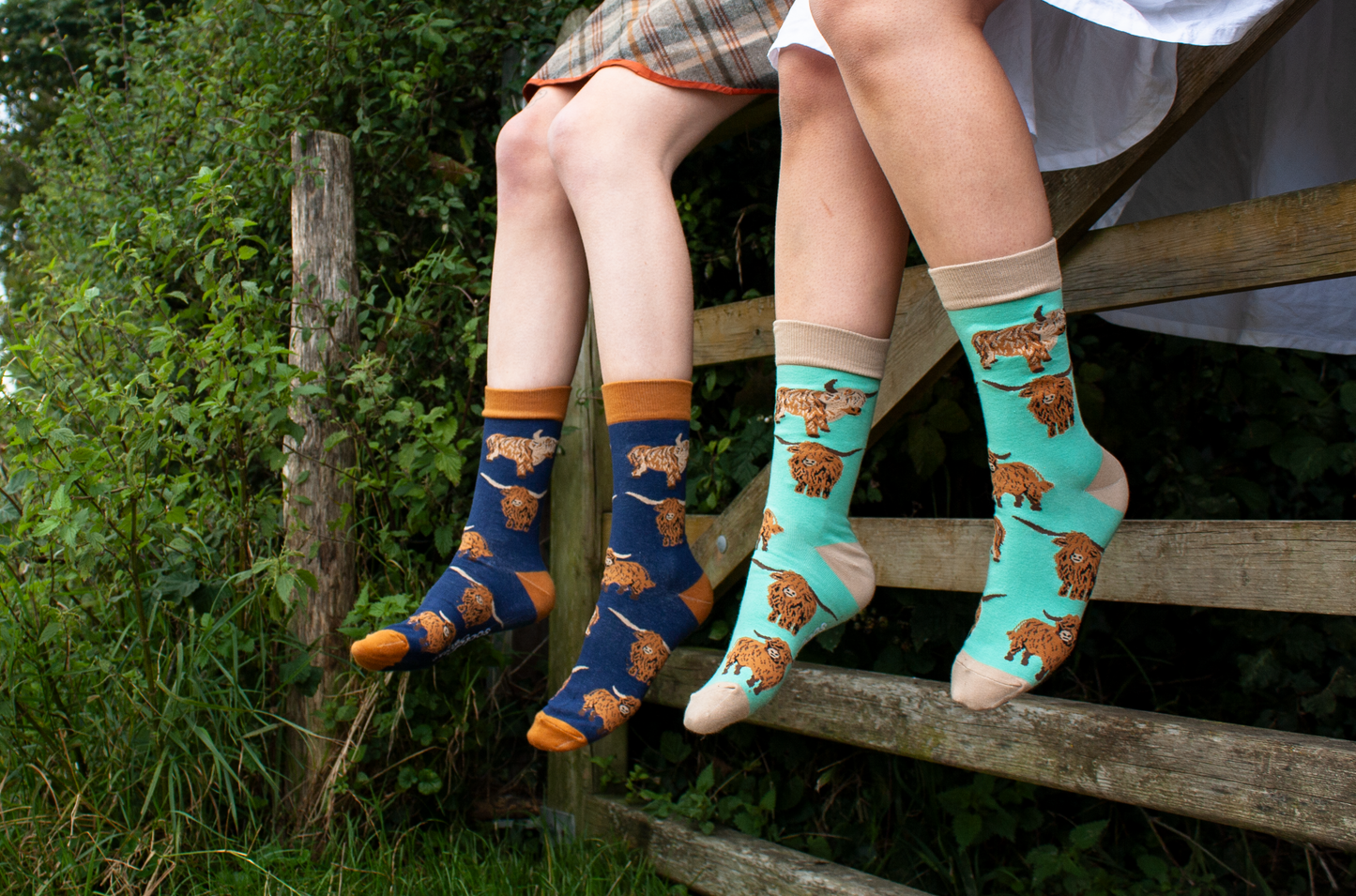 People sitting on a farm gate wearing Soctopus socks. 