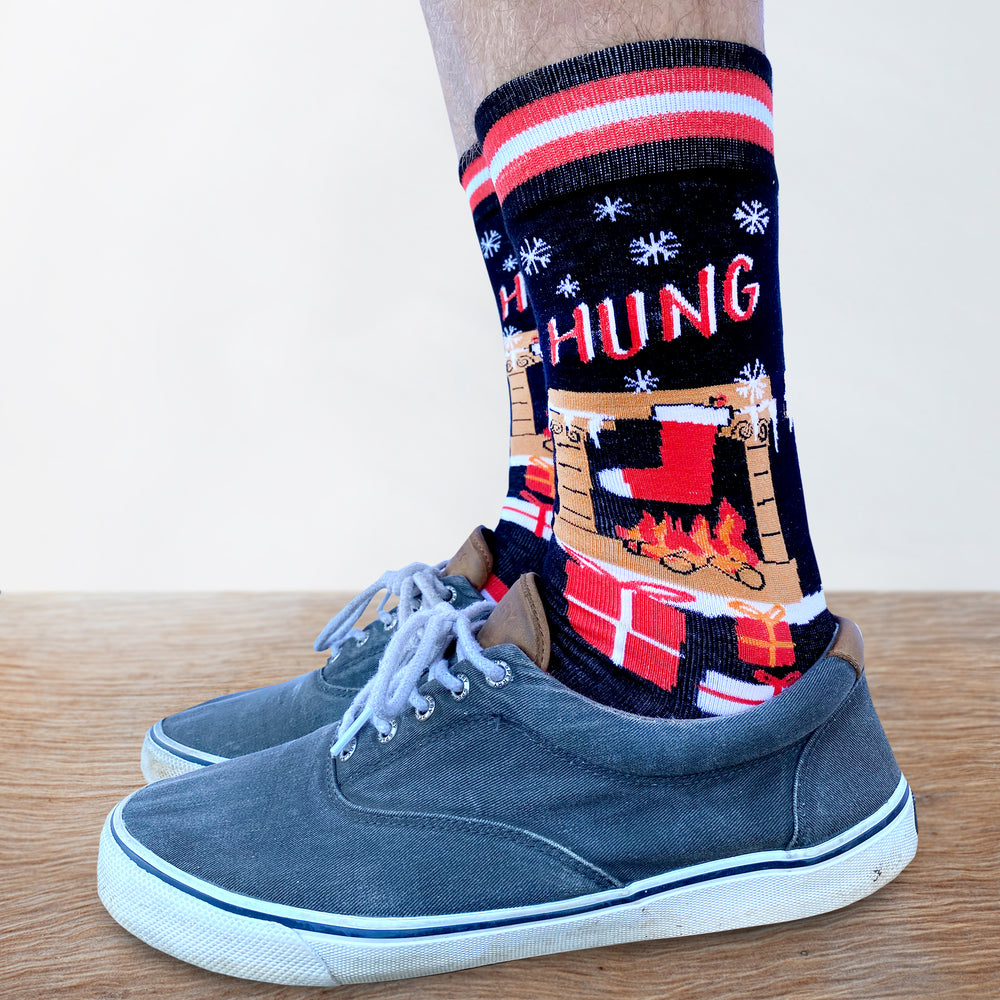 
                      
                        A pair of Christmas themed socks with a stocking hanging over a  fireplace. Striped toes and cuff. Red heel. 
                      
                    