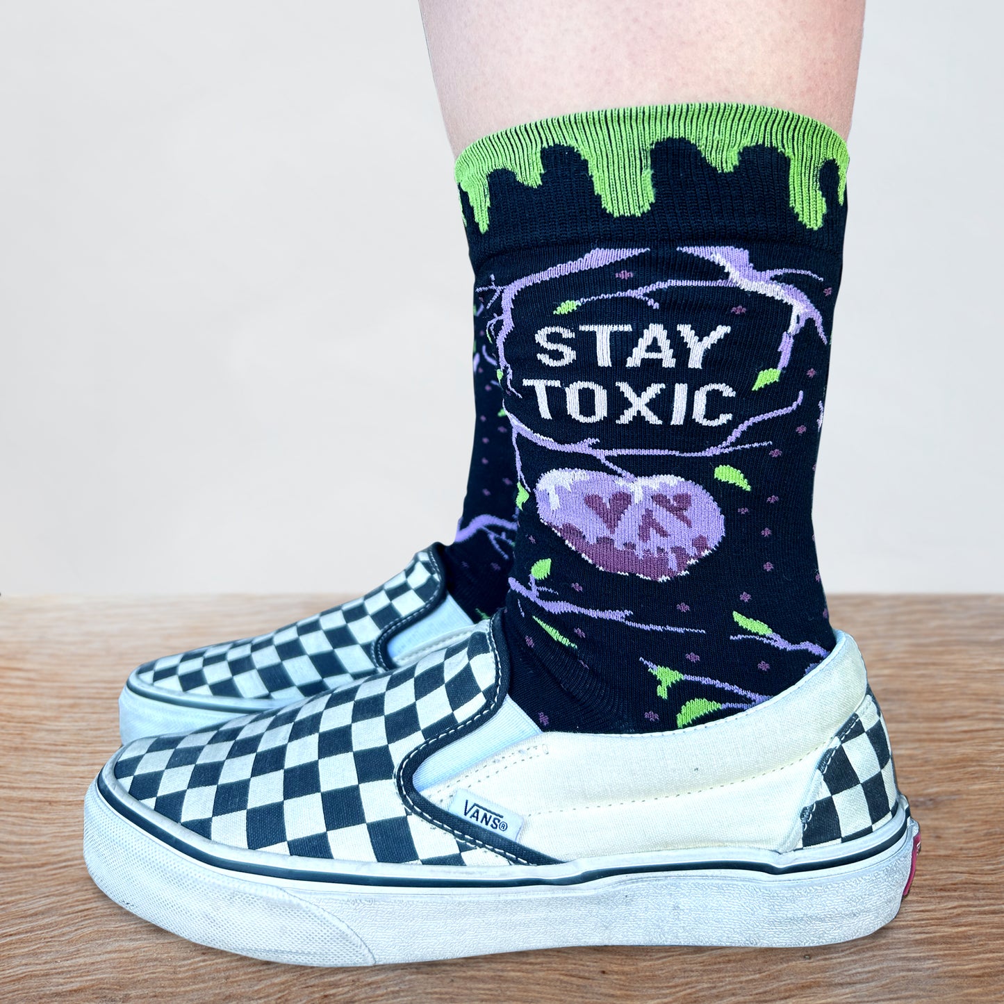 
                  
                    Model wearing a pair of socks with a purple and green toxic waste and Halloween motif. 
                  
                